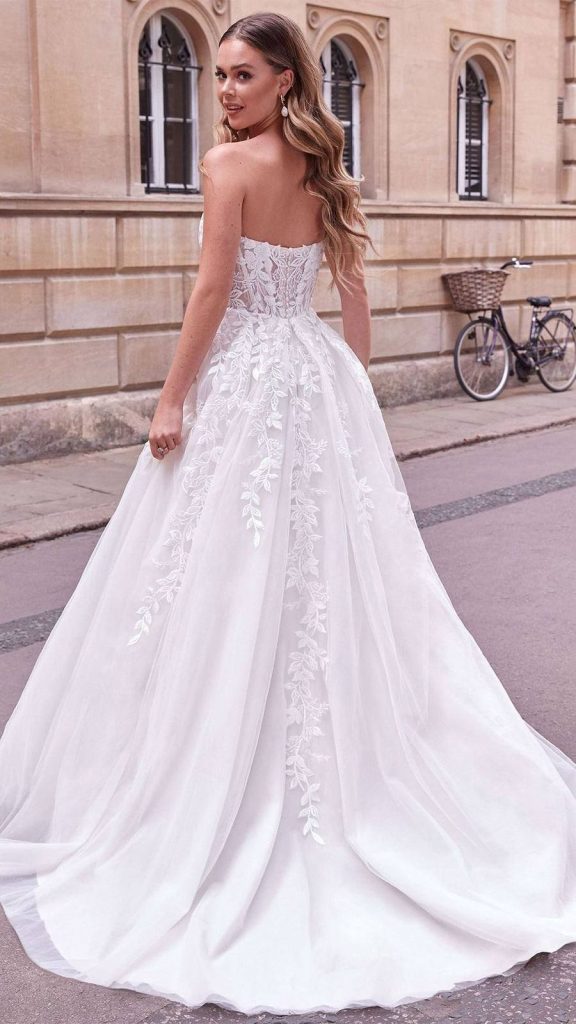 Back view of a strapless ball gown with cascading leaf lace and a long tulle train
